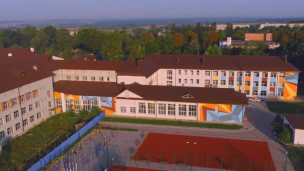 Skolbyggnad och skolgård på morgonen. Basket lekplats avdelning träd. Lekplats — Stockvideo