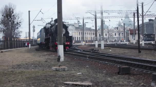 Dampflokomotivzug nähert sich Bahnhof und passiert Güterbahnhof — Stockvideo
