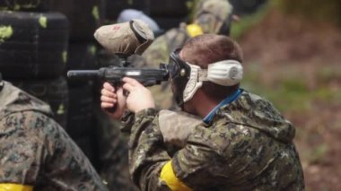 Paintball oynayın, silahlı oyuncular. Üniformalı ve maskeli ressamlar.