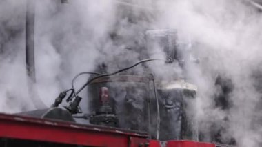 Treni kaplayan duman. Retro buharlı lokomotif tren istasyonundan ayrılıyor. Eski siyah buhar treni