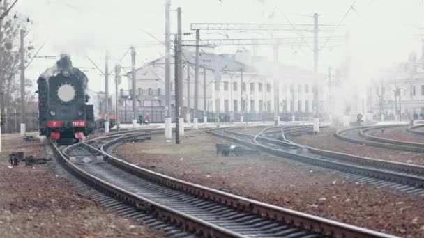Train de locomotive à vapeur approchant d'une gare passant par une gare de marchandises — Video