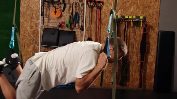 男子在体操馆训练带桁架的手臂，在空中训练俯卧撑身体上部胸部 — 图库视频影像