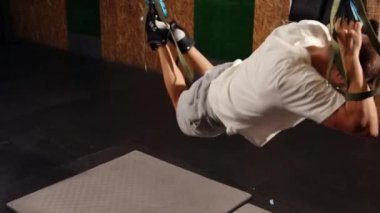 Çok çalışıyorum. Atletik bir adamın yan görünüşü, spor kıyafetleri içinde mükemmel bir vücut Trx fitness ile havada asılı.