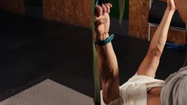 Süspansiyon askısı takan bir adam. Trx 'i tutarken havada şınav çeken genç bir adam. Yakışmış.