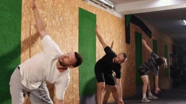 Genç ve kötü iş adamları sağlıklı eğik kollar ve sırt pozisyonu, karakter egzersizleri. Kişisel fitness erkek eğitmeni eğitimcilere içeride kasları esnetme konusunda yardımcı oluyor..