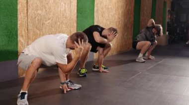 Spor salonundaki fitness antrenmanından önce genç bir adam. Sağlıklı genç adamlar içeride ısınıyor. Spor kıyafetleri içindeki güzel insanlar spor yapmadan önce esneme hareketleri yapıyorlar.