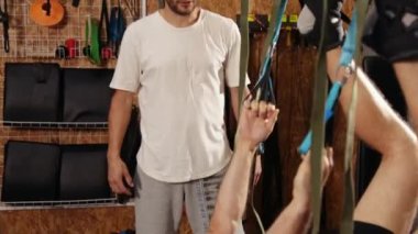 Sinek yogası yapan yakışıklı genç adam spor salonunda spor salonunda spor yaparken trx fitness kayışlarıyla esneme egzersizleri yapıyor. Spor sağlıklı yaşam tarzı konsepti. Antrenör monitör egzersizi.