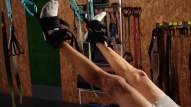 Süspansiyon askısı takan bir adam. Trx 'i tutarken havada şınav çeken genç bir adam. Eğitimdeki spor kayışlarıyla sinek yogası esneme egzersizleri yapan yakışıklı bir erkek. Sporcu vücut gerer