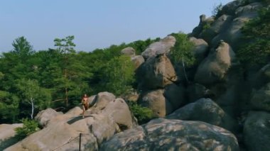 Kadın avuçlarıyla dizlerine dokunarak zıplıyor. Güzel bir bayan sabah boyunca rock 'ta antrenman yapıyor. Hava fotoğrafçılığı