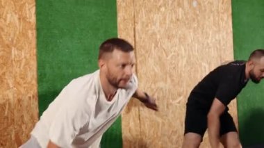 Spor kıyafetleri içinde oldukça aktif fitness adamları spor salonunda atlama egzersizleri yapıyorlar. Beden dersinde spor yapan bir adam. Spor giyinen adam atlama egzersizi yapıyor, neşeyle zıplıyor, uzun boylu.