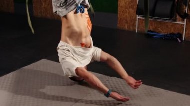 Süspansiyon askısı takan bir adam. Trx 'i tutarken havada şınav çeken genç bir adam. Güzel erkek, uçuş yogası yapıyor. Egzersiz yapıyor. Antrenmanlarda spor kayışlarıyla esnetiyor.