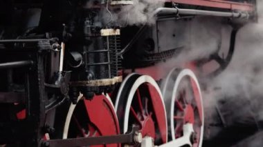 Eski tekerlekler ve buhar makinesinin parçaları. Sovyet lokomotifi istasyon platformunda duruyor. Hareket halinde buharlı vintage trenler.