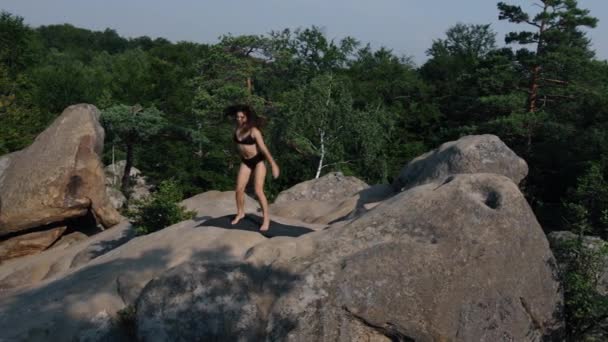 여자가 매트에 앉아서 점프하고 아름다운 아침에 위에서 운동을 — 비디오