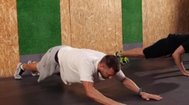 Güçlü ve formda sporcular çatı katı tarzı bir endüstriyel spor salonunda egzersiz yapıyor. Fitness antrenmanı. Yetişkinlerden oluşan bir grup, kapalı alanda fiziksel kondisyon egzersizleri yapıyor.