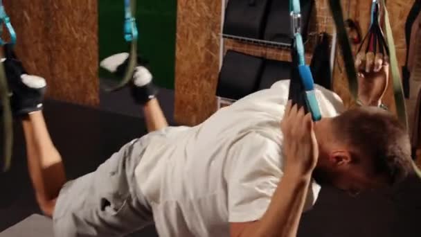 ジムでTrxフィットネスストラップを持つ男性のトレーニング腕は 空気列車の上体胸肩の側面のトリップでプッシュを行う 体育の概念で運動する人々 選手が立ち上がる — ストック動画