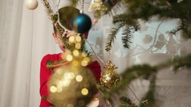 Genç çocuk noel ağacının arkasına saklanıyor, gülümseyen delikanlı saklanıyor, komik küçük çocuk noel ağacına bakıyor..