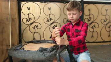 Çocuk sandalyeyi tornavidayla tamir ediyor vidaları söküyor, vidayı sıkıyor, cıvata takıyor. Küçük usta. Çalışkan çocuk.