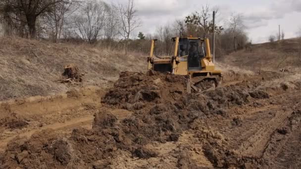 建筑工地的推土机把泥土铲成堆 强大的黄色推土机在竖井处碾碎沙子 铺路用推土机 商用车辆 — 图库视频影像
