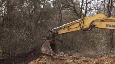 İnşaat alanında çukur kazarak kepçeyle çalışmak. Toprak kazmak için kazıcı kova dişleri. Toprakta sürüngen tarağı kazmak. Kazıcı. Toprak hareket eden araç. Kapat.
