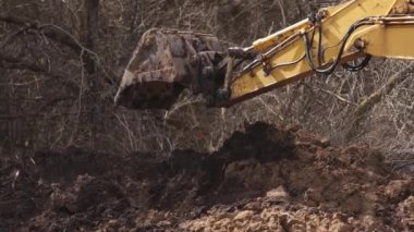 Sürüngen kazıcı. Kova kaldırma ile yapılan tarama inşaat alanında toprak kazıyor. Kazıcı inşaat alanında toprağı kazıyor. Kapat.