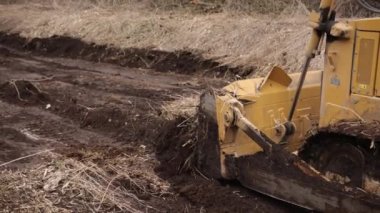 İnşaat alanındaki buldozer bir yığın toprağa toprak topluyor. Güçlü sarı toprak taşıyıcı ereksiyon alanında kumu parçalar. Yolu döşemek için buldozer, ticari araç. Kapat.