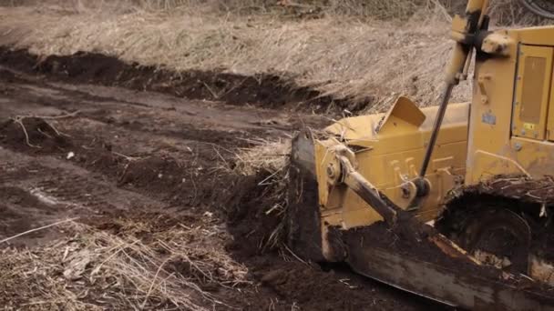 建筑工地的推土机把泥土铲成堆 强大的黄色推土机在竖井处碾碎沙子 铺路用推土机 商用车辆 靠近点 — 图库视频影像