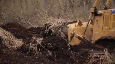 İnşaat alanındaki buldozer bir yığın toprağa toprak topluyor. Güçlü sarı toprak taşıyıcı ereksiyon alanında kumu parçalar. Yolu döşemek için buldozer, ticari araç..