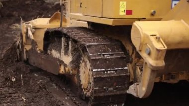 İnşaat alanındaki buldozer bir yığın toprağa toprak topluyor. Güçlü sarı toprak taşıyıcı ereksiyon alanında kumu parçalar. Yolu döşemek için buldozer, ticari araç. Kapat.