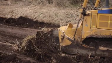 İnşaat alanındaki buldozer bir yığın toprağa toprak topluyor. Güçlü sarı toprak taşıyıcı ereksiyon alanında kumu parçalar. Yolu döşemek için buldozer, ticari araç. Kapat.