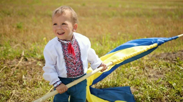 Son waving ukrainian flag on wheat field, lonely patriot man standing, looking at the sunrise with flag of ukraine. Happy boy is a patriot of his country. Yellow-blue symbol. Independence day