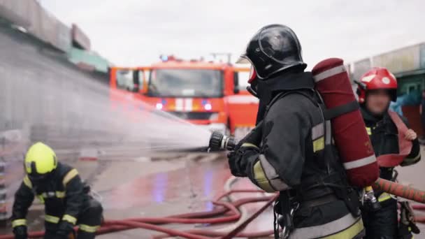 Een Brandweerman Bestrijdt Een Brand Een Brandweerwagen Staat Achtergrond Komt — Stockvideo