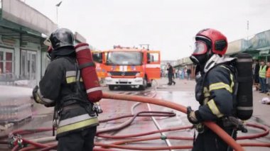 In the background, there is a fire truck with the sound of the fire truck sirens, and water pressure is coming from the hose