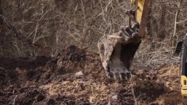 İnşaat alanında bir kova kazma toprağı. Sürüngen kazıcı kazısı. Kazı makinesi. Toprak taşıma ekipmanı. Kazı aracı. Ereksiyon işi. Kapat.