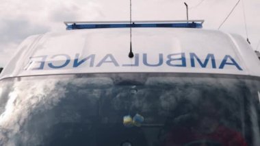 The ambulance van on a wide city street has warning lights and sirens, a Metropolitan rescue vehicle, responding in hazardous conditions, a close-up front view of the ambulance.