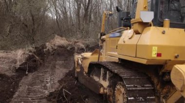 İnşaat alanındaki buldozer bir yığın toprağa toprak topluyor. Güçlü sarı toprak taşıyıcı ereksiyon alanında kumu parçalar. Yolu döşemek için buldozer, ticari araç..