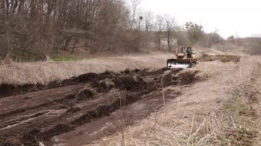 İnşaat alanındaki buldozer bir yığın toprağa toprak topluyor. Güçlü sarı toprak taşıyıcı ereksiyon alanında kumu parçalar. Yolu döşemek için buldozer, ticari araç..