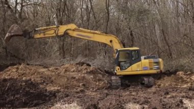 İnşaat alanında çukur kazarak kepçeyle çalışmak. Toprak kazmak için kazıcı kova dişleri. Toprakta sürüngen tarağı kazmak. Kazıcı. Toprak hareket eden araç.