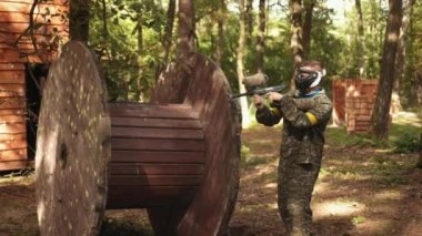 Paintball is an action-packed, adrenaline-pumping sport played outdoors with friends wearing camouflage and protective masks. Participating in leisure activities.
