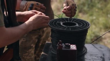 Soldier in camouflage with explosives in his hands, anti-terrorist team combat engineer, ammunition technical officer, explosives military expert, miner preparing explosive device before explosion.