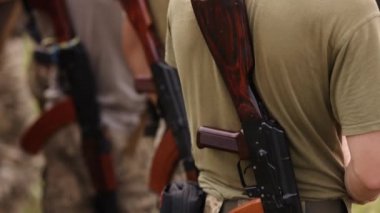 Ukrainian soldiers stand at the checkpoint, dressed in military uniforms, with Kalashnikov rifles behind their backs, close up