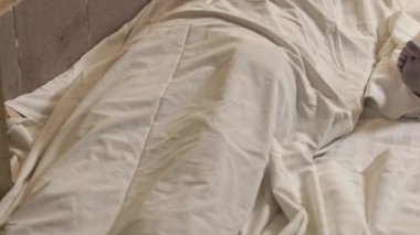 Human corpse covered with a sheet in morgue. Homo dead comprise with sheet. Human corpse covered with bedsheet, in morgue. Death from covid-19 and protection from virus global.