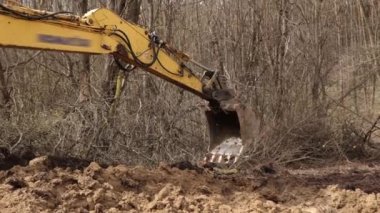 İnşaat alanında bir kova kazma toprağı. Sürüngen kazıcı kazısı. Kazı makinesi. Toprak taşıma ekipmanı. Kazı aracı. Ereksiyon işi. Kapat.