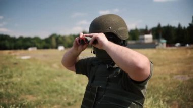 A soldier looks through binoculars, a Navy SEAL scout in battle dress and helmet, observes the area, searches targets, monitors enemy movements, and directs artillery fire.