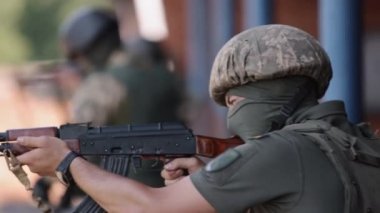 An army man in a green uniform vest is unloading a machine gun, lying on ground with a weapon, ready to attack, machine gun crew of corps is firing, and army gunner is firing at enemy.