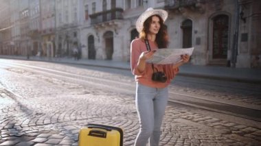 Slow motion, hipster girl holds tourist map, enjoying vacation, lady walking down street, looking for way using paper map in old town, travelling in Europe, exploring beautiful sights. Go Everywhere