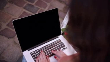Womans hands work on the keyboard with mock up screen computer. Creative people can put anything on computer screens. Womans hands type on a keyboard outside. Laptop with green screen and chroma key