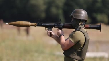 Askeri üniforma, miğfer ve çelik yelek giyen bir asker, Omuz-Ateşli Roket Fırlatıcı RPG-7 PSRL-1 'i tam olarak düşmana doğru ateşler.