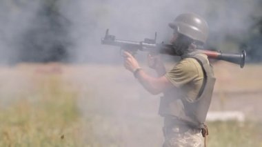 Hassas bir roketle, miğferli ve askeri üniformalı bir asker Hassas Omuz Ateşli Roket Roketatar RPG-7 PSRL-1 ile düşmana ateş ediyor.