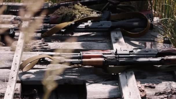 兵士が手を閉じると 機関銃Kalashnikov Ak47が木製の板にセットされており 武器の訓練のために準備されており 周りにかなりの数のライフルがあります — ストック動画