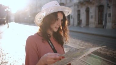 Young woman exploring beautiful sights in Europe, slow motion, hipster girl holding tourist map, enjoying holiday, lady walking down street, using paper map in old town to find her way. Go Everywhere